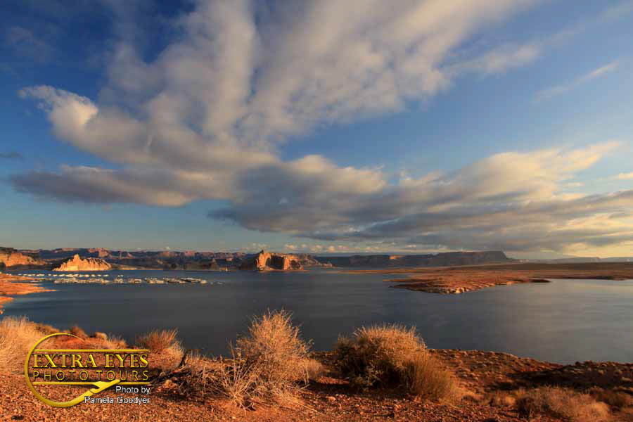 lake powell with clouds with the desert in the foreground and the big blue lake.
